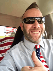 a man wearing sunglasses is giving a thumbs up while sitting in a car