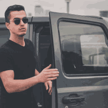 a man wearing sunglasses is standing next to a car