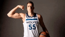 a basketball player for the wolves is flexing his muscles while holding a basketball