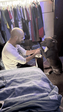 a man sitting on a bed with a can of beer and a dog sitting on its hind legs