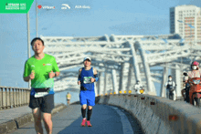 a man in a green shirt is running on a bridge sponsored by aia