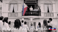 a group of people standing in front of a building with the words " itabuhay ang filipinas " on the bottom