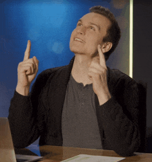 a man sitting at a desk with his fingers up