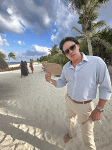 a man is holding a fan on the beach