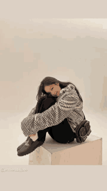 a woman in a zebra print jacket sits on a cube