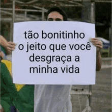 a man is holding a sign that says tão bonitinho o jeito que voce desgraca a minha vida