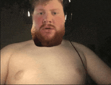 a shirtless man with a beard and headphones on