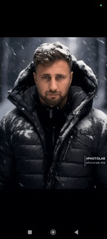 a man in a black jacket with a hood is standing in the snow