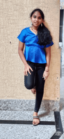 a woman in a blue shirt and black pants is standing on one leg