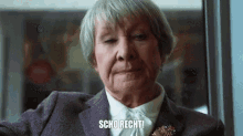 an older woman with gray hair is wearing a purple jacket and a brooch and says scho recht .