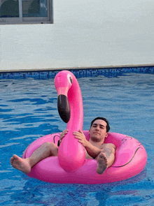 a man is floating on a pink flamingo in a pool