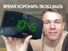 a man is holding up a philips clock that reads 10:45