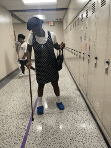 a woman in a polka dot dress is walking down a hallway with a cane