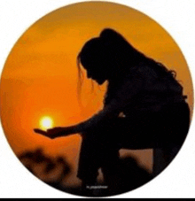 a silhouette of a woman holding the sun in her hand in front of a sunset .