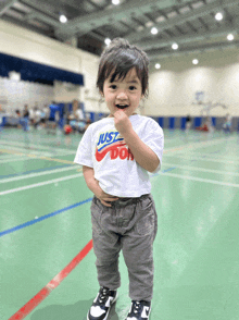 a little boy wearing a white shirt that says just do