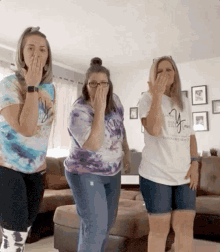 three women are dancing in a living room with one wearing a shirt that says ' i love you ' on it