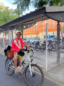 a woman wearing an orange vest and a helmet is riding a bike