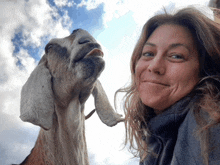 a woman and a goat are posing for a picture and the goat is sticking its tongue out