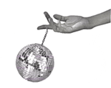 a hand is holding a small disco ball on a chain .