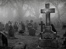 a black and white photo of a cemetery with a cross in the foreground and a gravestone that says thomas