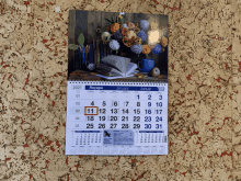 a calendar with a picture of a vase of flowers is hanging on a wall