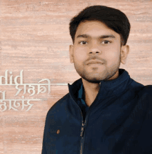 a young man stands in front of a wall that says did