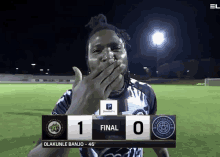 a soccer player covering his mouth while holding a scoreboard that says final