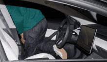 a person is kneeling down in a car with a tablet on the dashboard