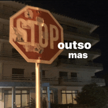 a stop sign in front of a building with outso mas written below it