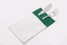 a knife and fork are in a white napkin with a green border