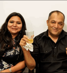 a man and a woman are sitting next to each other and the woman is holding a cup