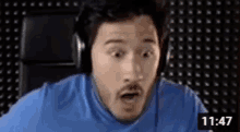 a man wearing headphones is making a surprised face while sitting in front of a computer screen .