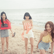 three women standing on a beach with one wearing a beach club t-shirt