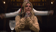 a woman sitting at a table with her hands folded and the words dryedmangoes.com on the bottom right