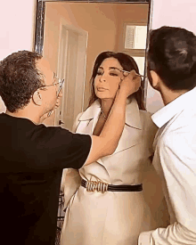 a woman in a white coat is getting her eyebrows done by a man in a black shirt