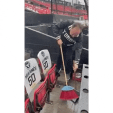 a man is cleaning the seats in a stadium with a mop .