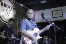 a man singing into a microphone in front of a sign that says rocket 07