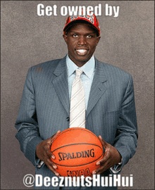 a man in a suit holds a spalding basketball