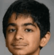 a close up of a young boy 's face with black hair .