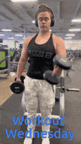 a woman wearing headphones is lifting dumbbells in a gym with the words " workout wednesday " on the bottom