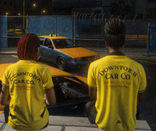 two women wearing yellow shirts with downtown car co on the back