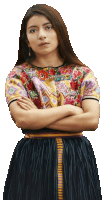 a woman with her arms crossed wearing a floral top and a black skirt