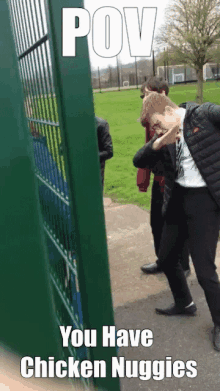 a group of people are standing in front of a green fence with the caption " pov you have chicken nuggies "