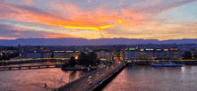 a bridge over a body of water with buildings in the background and a sunset