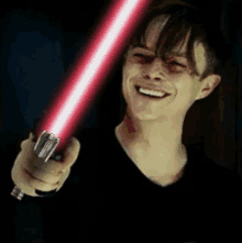 a man is holding a red light saber in his hand .