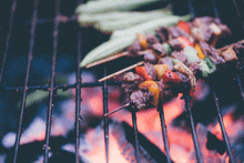 skewers of meat and vegetables are cooking over a fire