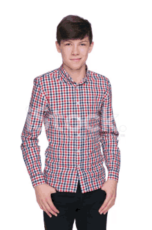 a young boy wearing a plaid shirt and black pants stands with his hands in his pockets