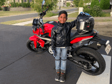 a young boy is standing next to a red motorcycle with a license plate that says 728-vk