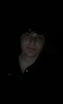 a young man is taking a selfie in the dark with his phone .