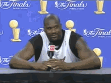 a man is sitting at a table with a microphone in front of a blue wall that says the finals